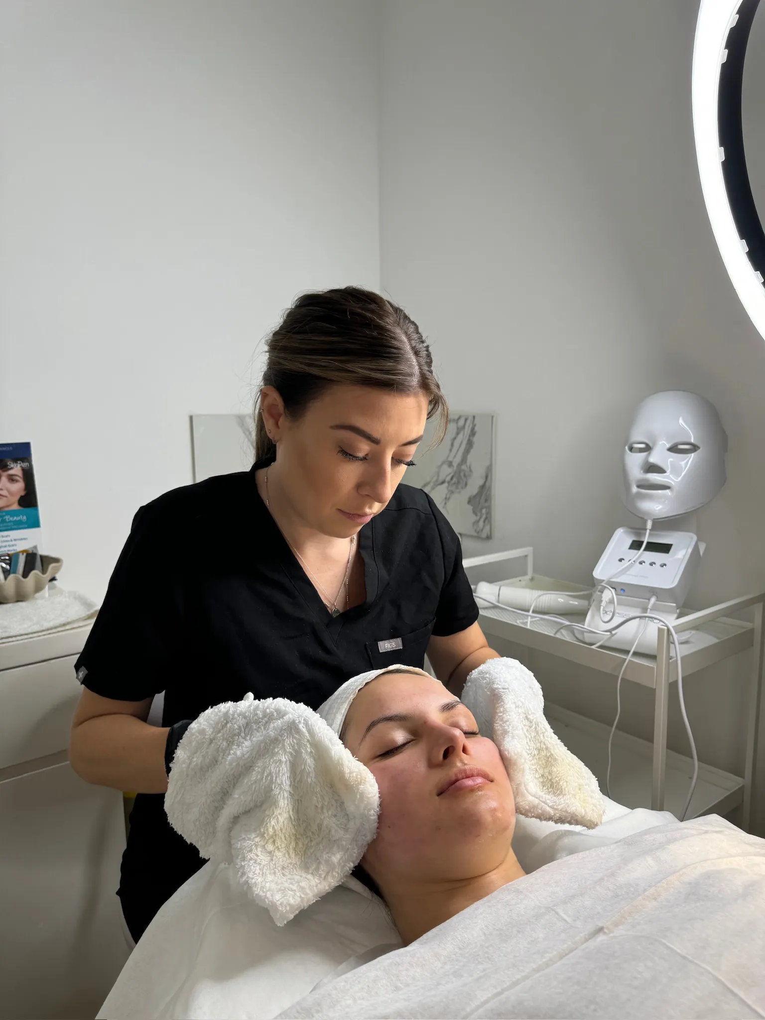 Emma gently cleansing a client’s face with soft mitts
