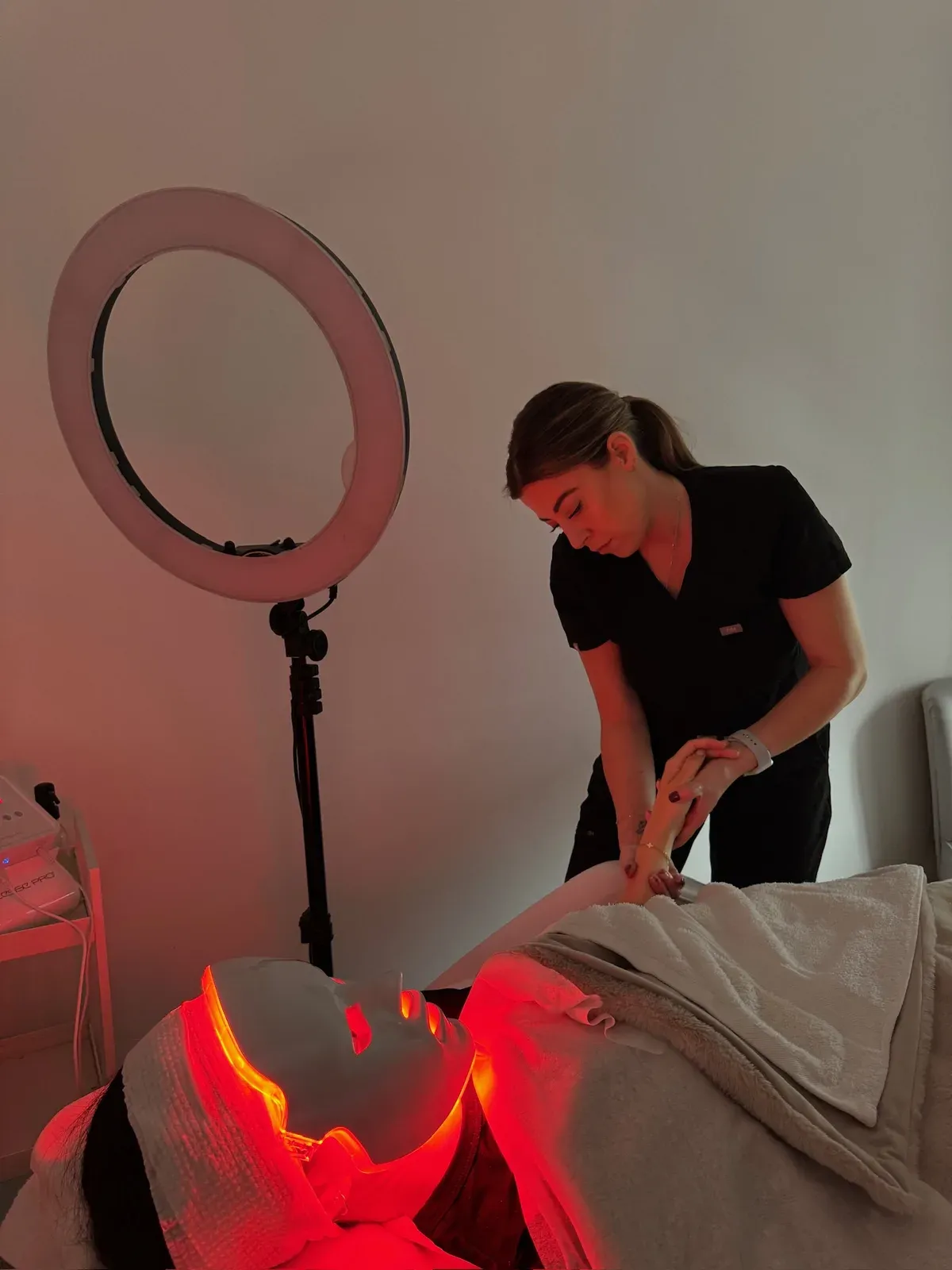 Emma beside a client under the red LED light