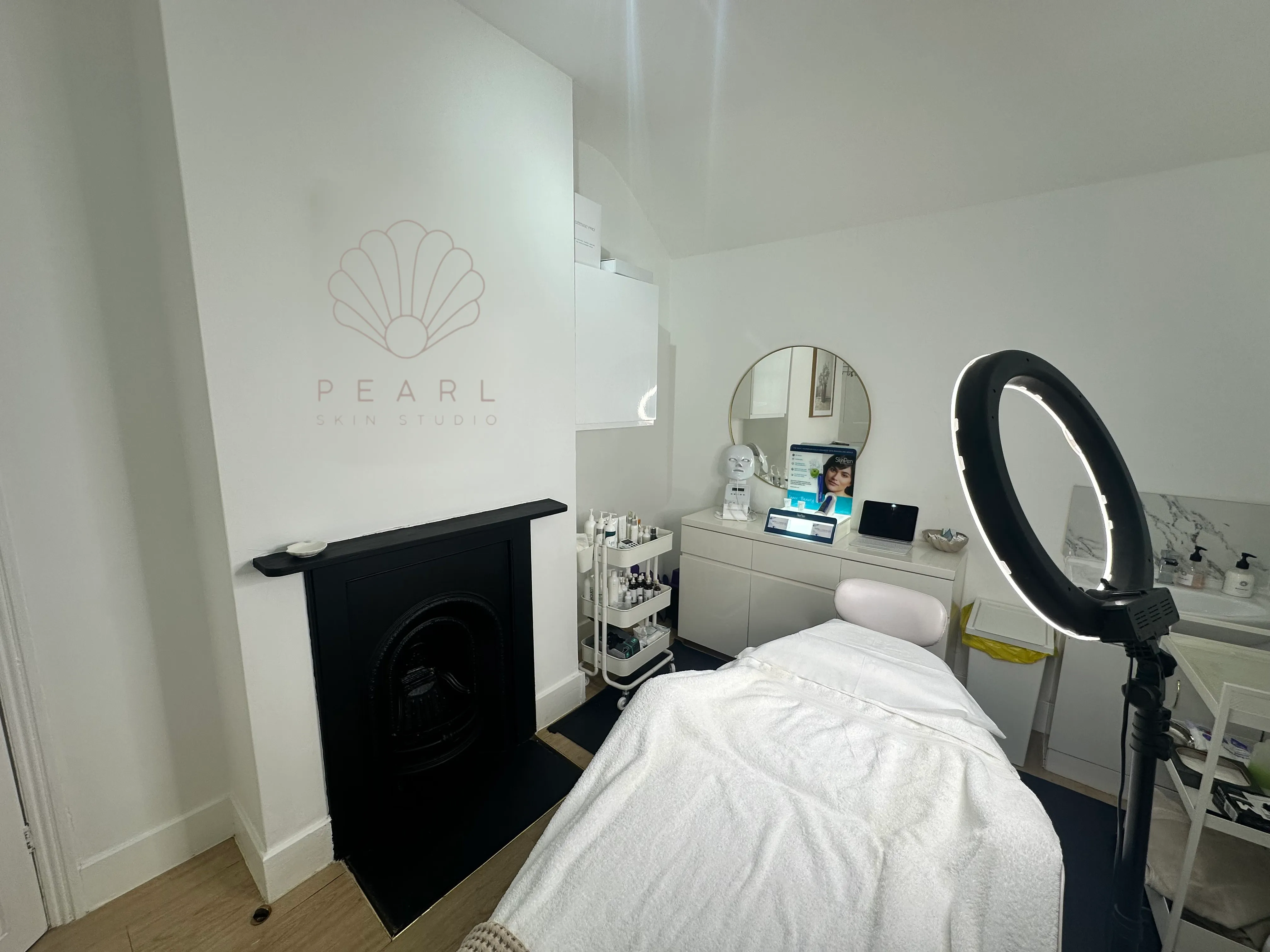 The fireplace with the Pearl logo above it, the mirror and details inside Pearl Skin Studio